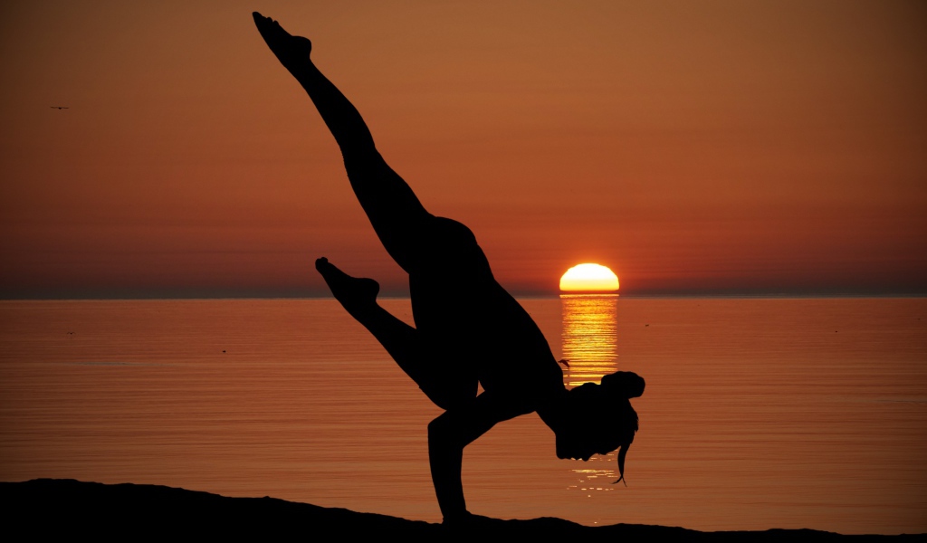 Девушка занимается йогой на закате солнца