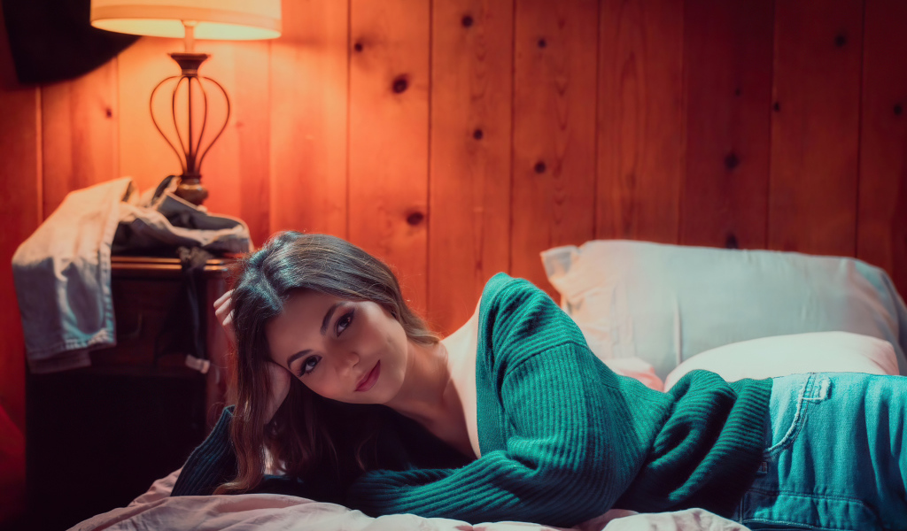 Актриса  Виктория Джастис в зеленом свитере на кровати