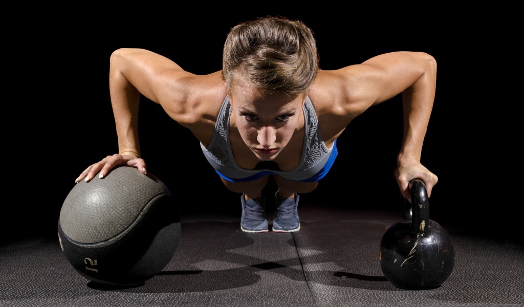 Девушка отжимается с гирями