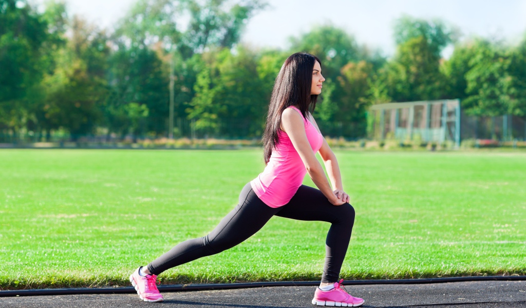 Девушка делает растяжку на поле 