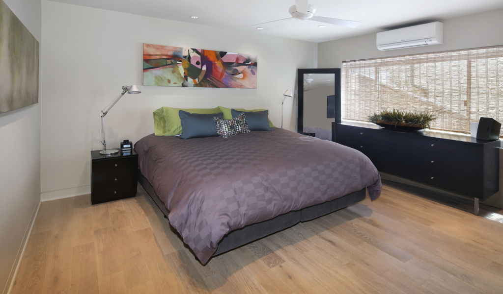 Большая серая кровать в спальне с белыми стенами