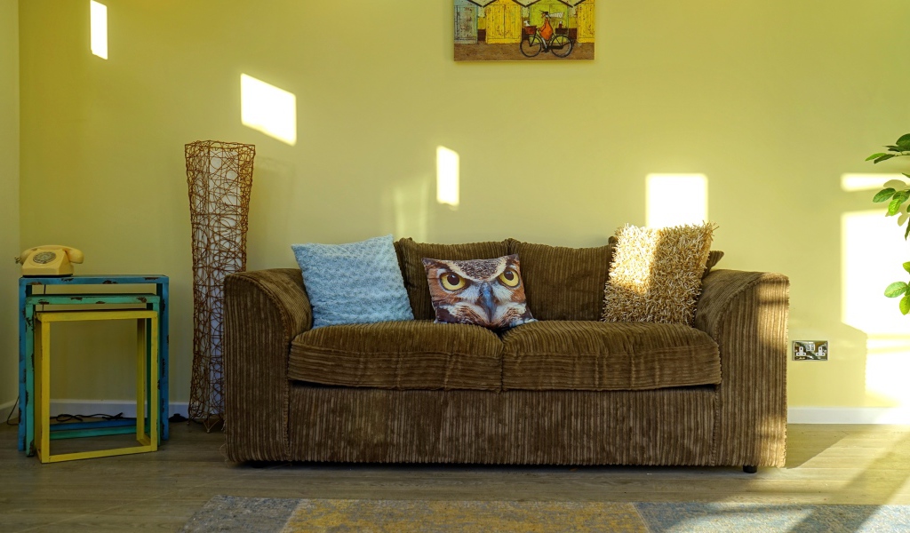 Большой старый диван в комнате с желтыми стенами