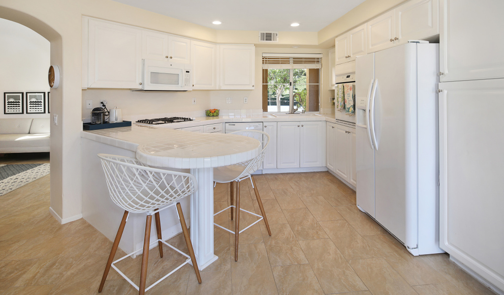 Большой холодильник и белая мебель на кухне 