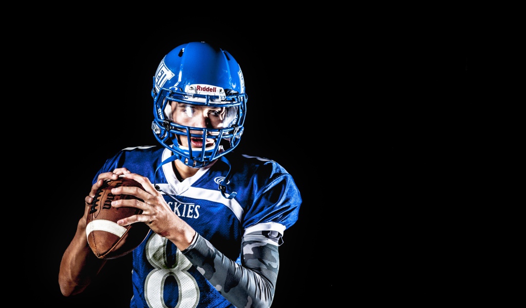 Мужчина игрок в американский футбол на черном фоне