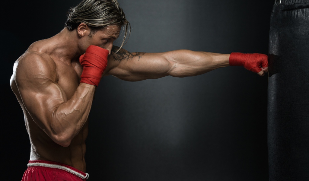 Мужчина боксер с грушей на сером фоне  