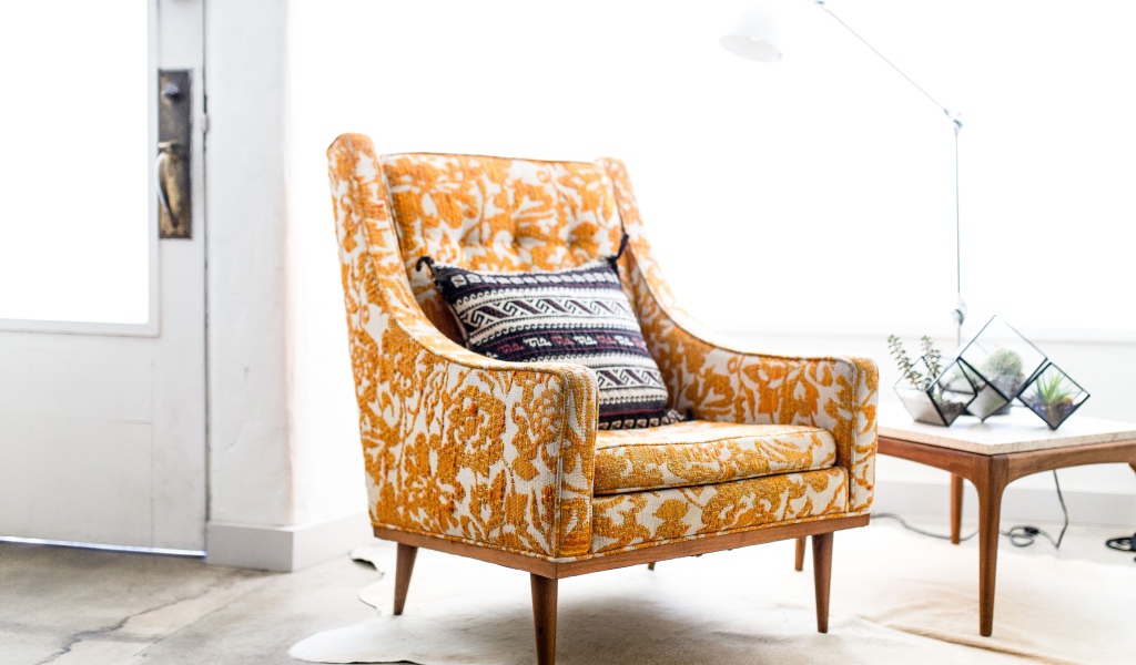 Старое кресло с подушкой в комнате 