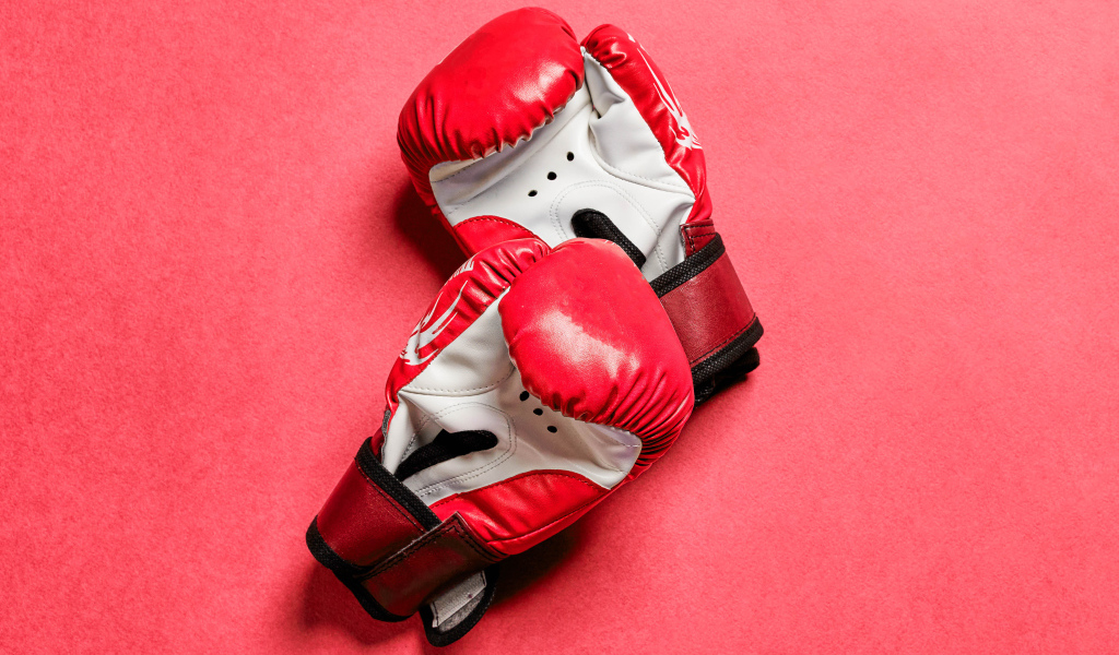 Красные боксерские перчатки на розовом фоне 