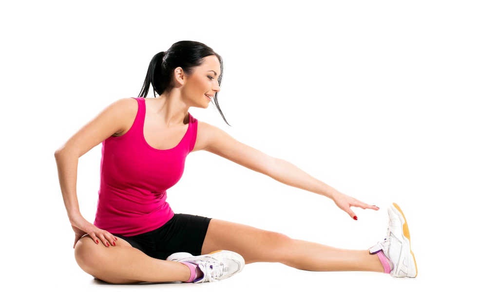 Спортивная девушка делает растяжку на белом фоне 