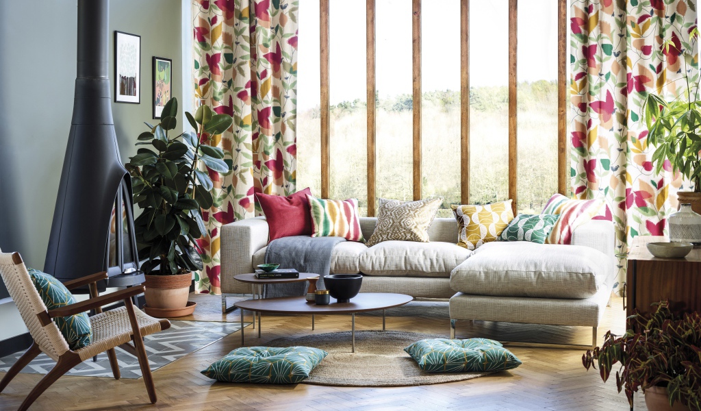 Белый диван с подушками стоит у окна