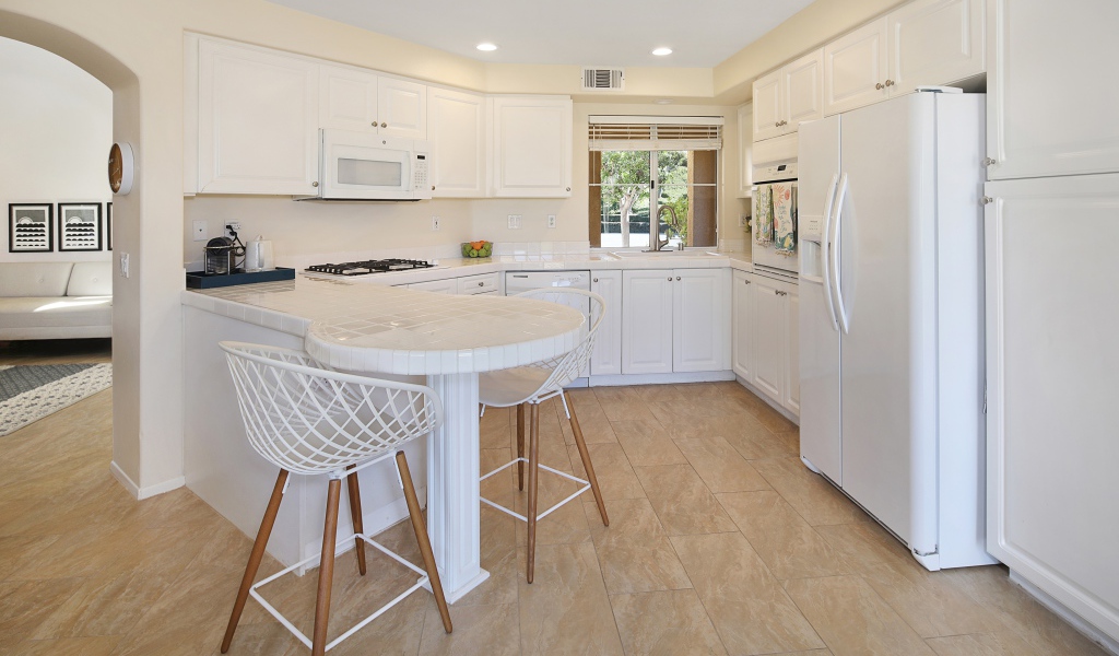 Белая стильная мебель с большим холодильником на кухне