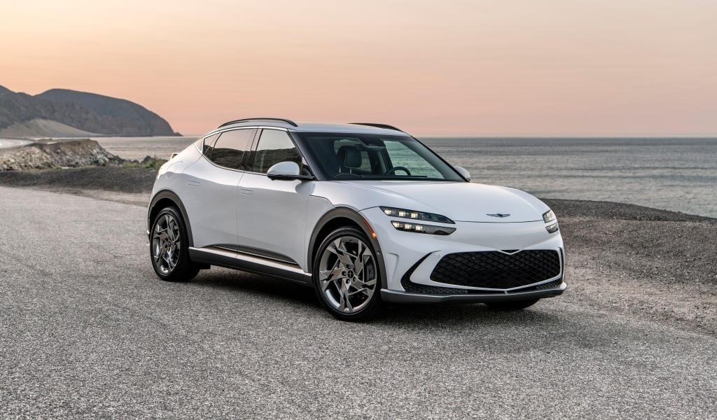 Белый автомобиль Genesis GV60, 2023 года на пляже