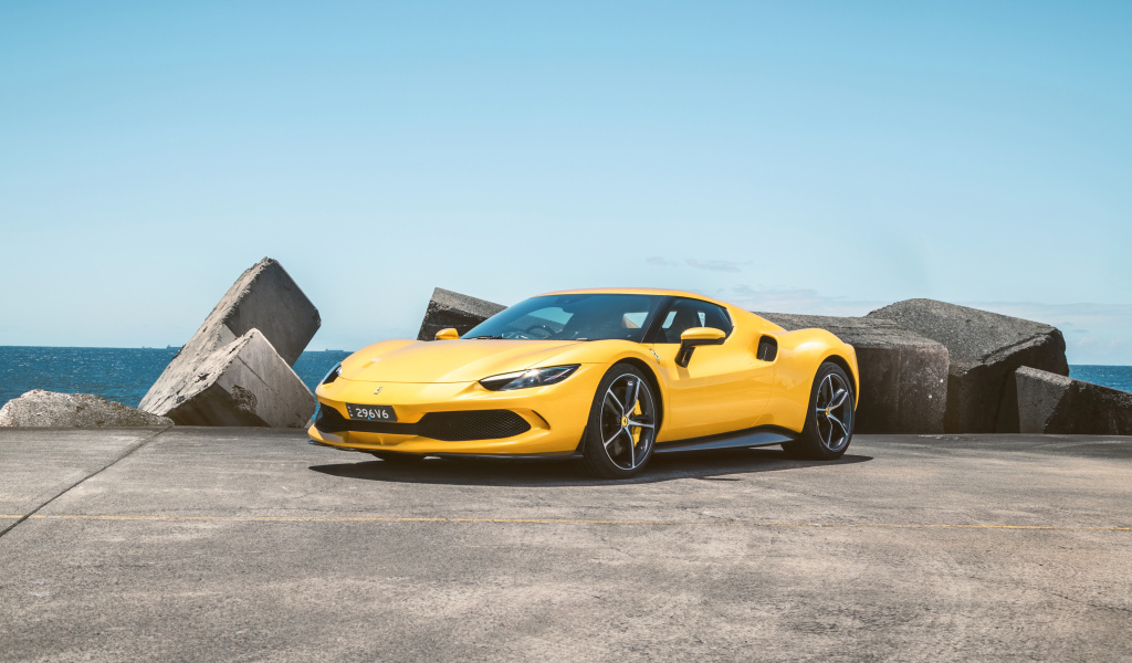 Желтый автомобиль Ferrari 296 GTB у камней