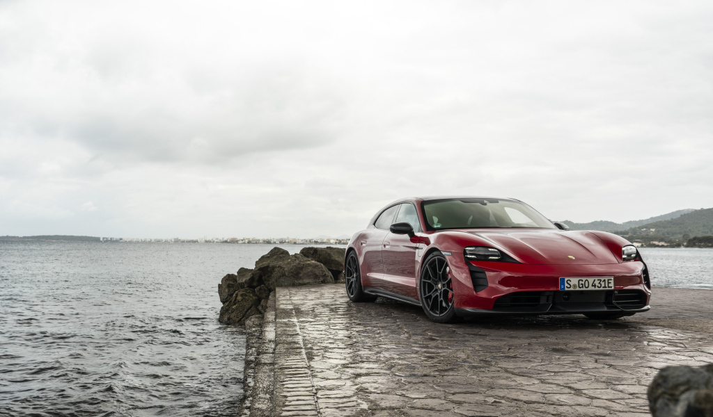 Красный автомобиль Porsche Taycan  у воды