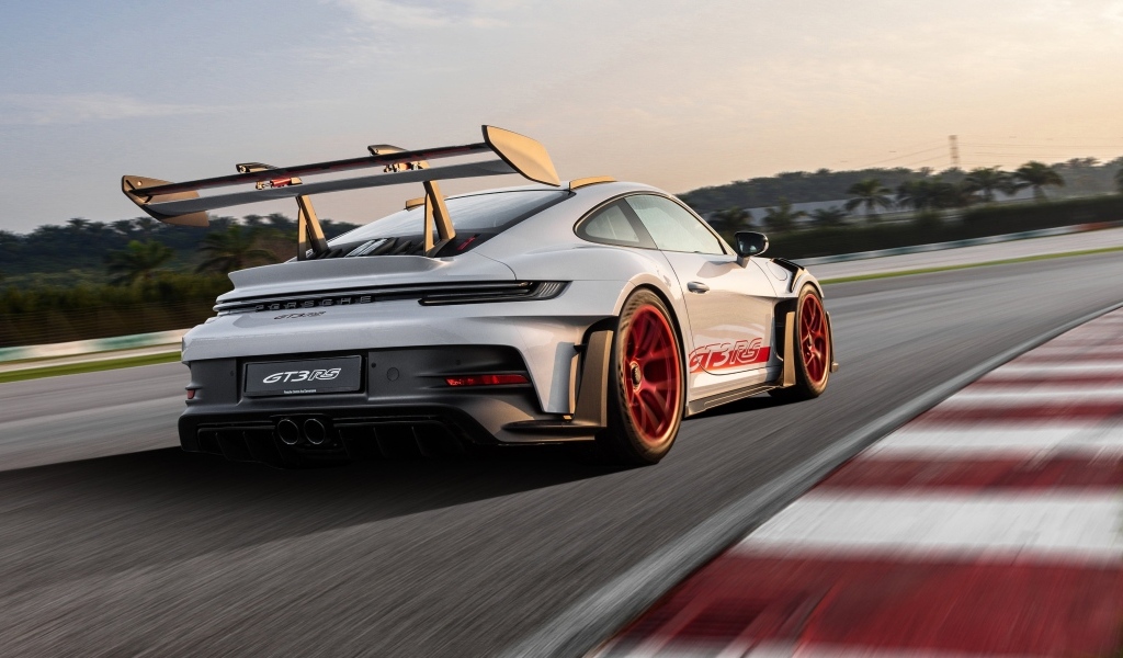 Серебристый спортивный автомобиль Porsche 911 GT3 RS Weissach Package 2023 года на трассе
