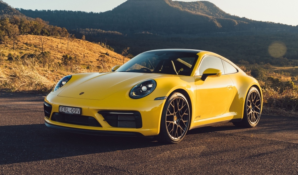 Желтый быстрый автомобиль Porsche 911 Carrera GTS вид спереди
