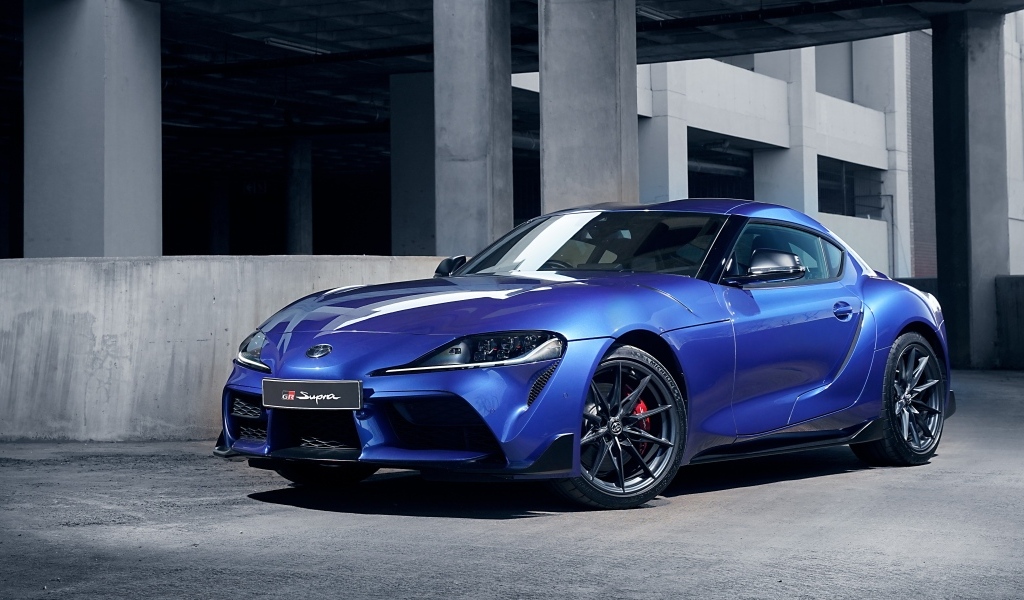 Синий автомобиль Toyota GR Supra 3.0 MT 2023 года у серого здания