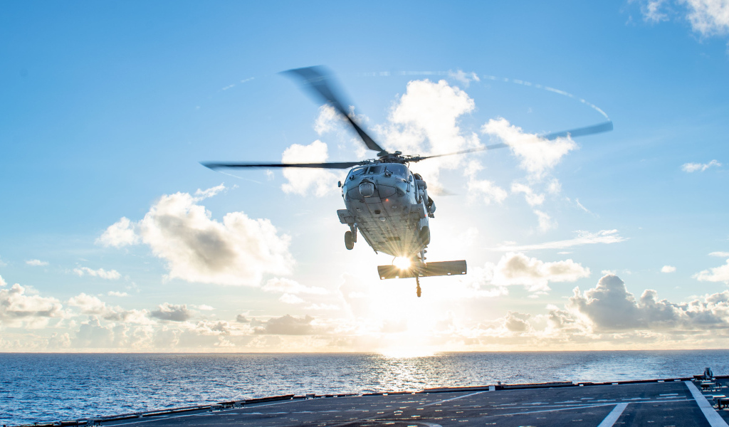 Military helicopter lands on a ship at sea