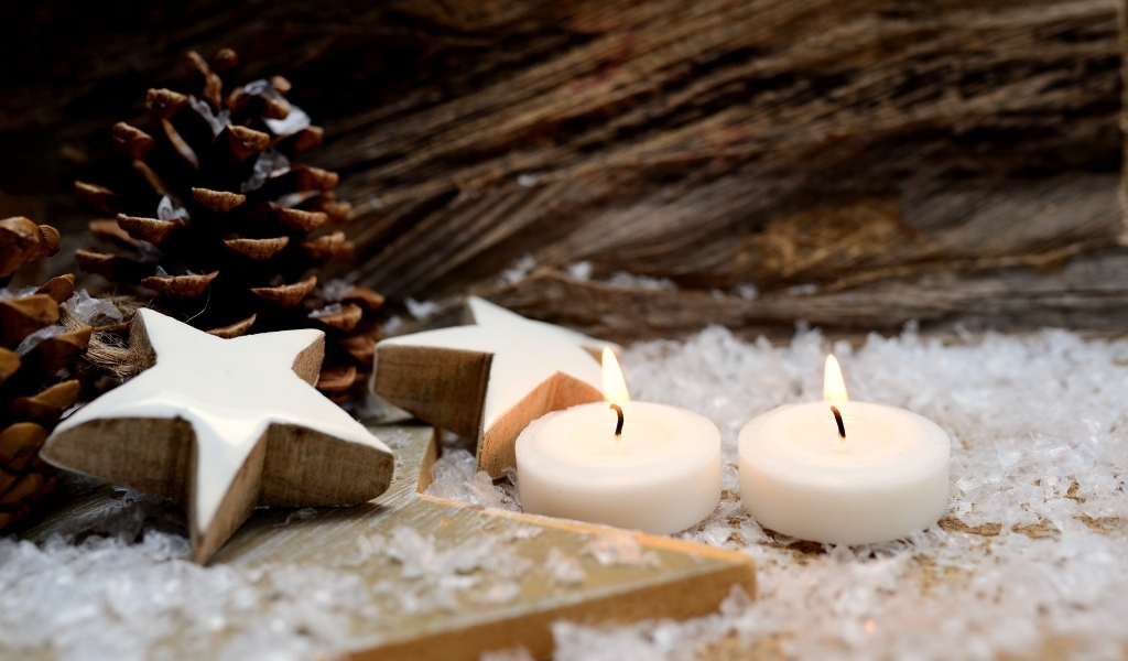 Две зажженные свечи, шишки и звезды
