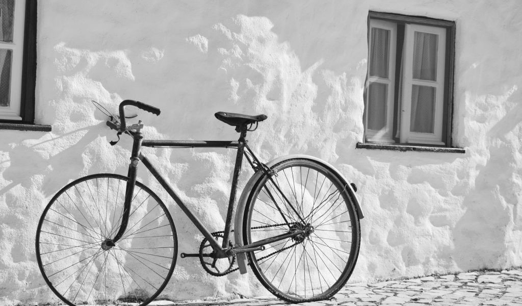 Черный велосипед стоит у белой стены