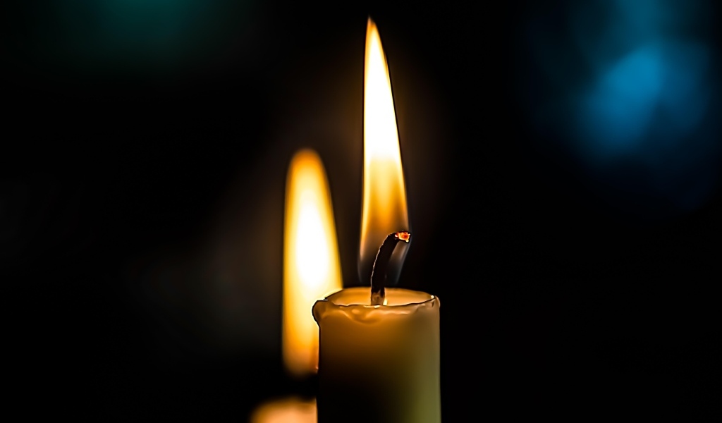 Зажженная свеча на черном фоне