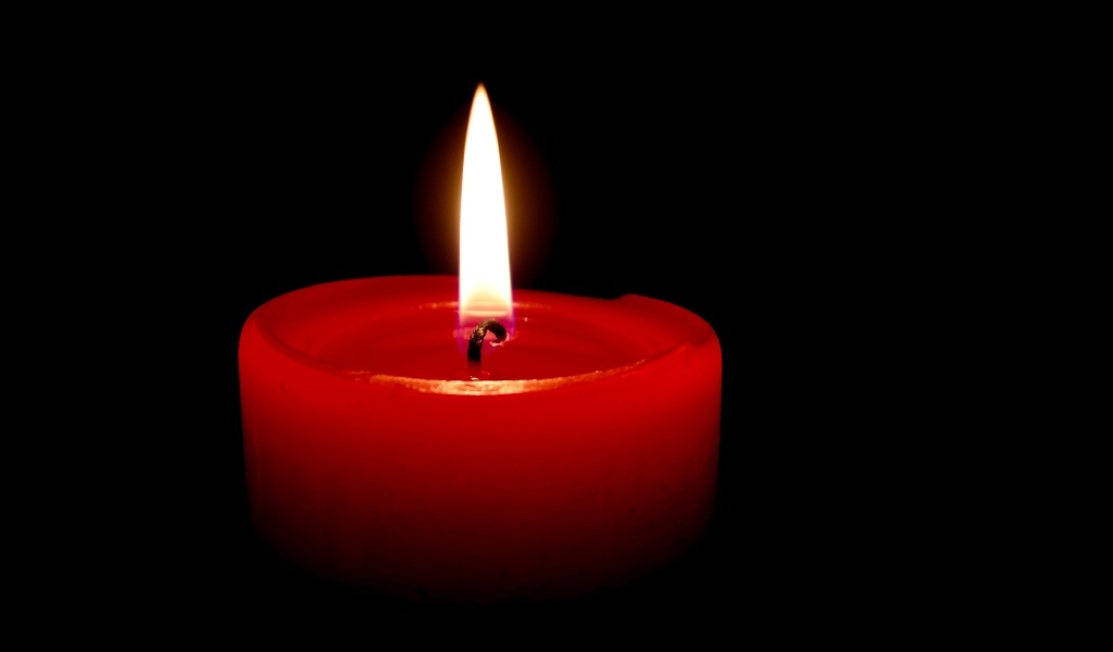 Зажженная красная свеча на черном фоне