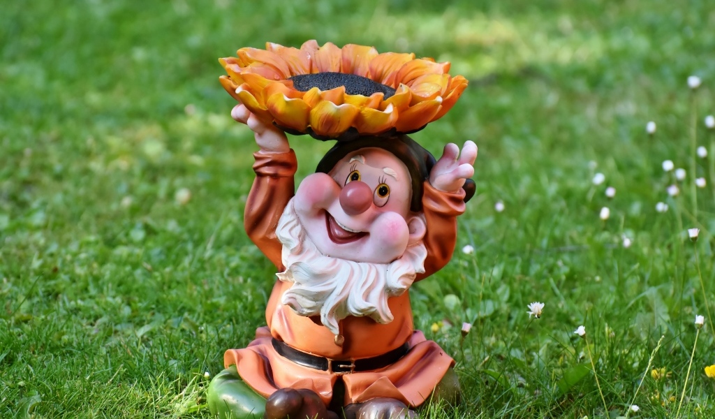 Садовая фигура гном за зеленой траве