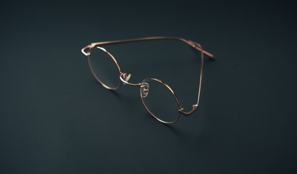 Очки лежат на серой поверхности