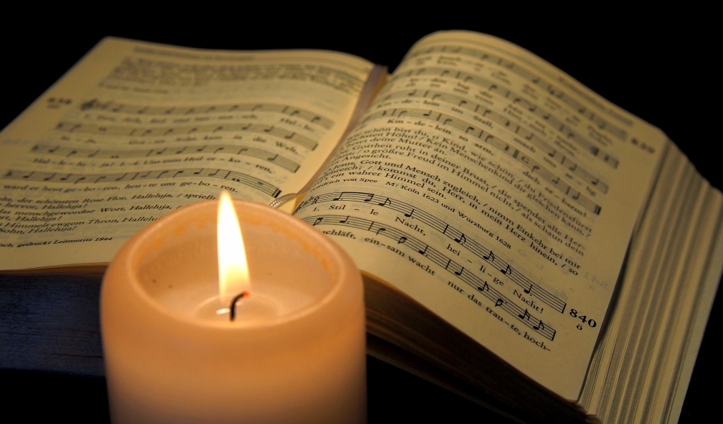 Зажженная свеча с книгой с нотами