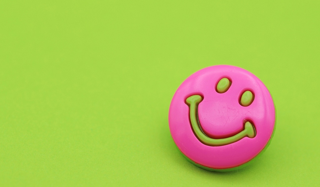 Розовый смайлик на зеленом фоне