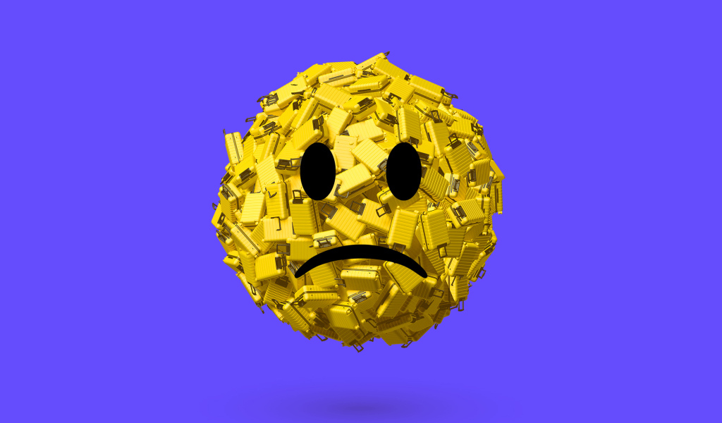 Грустный смайлик из чемоданов на синем фоне