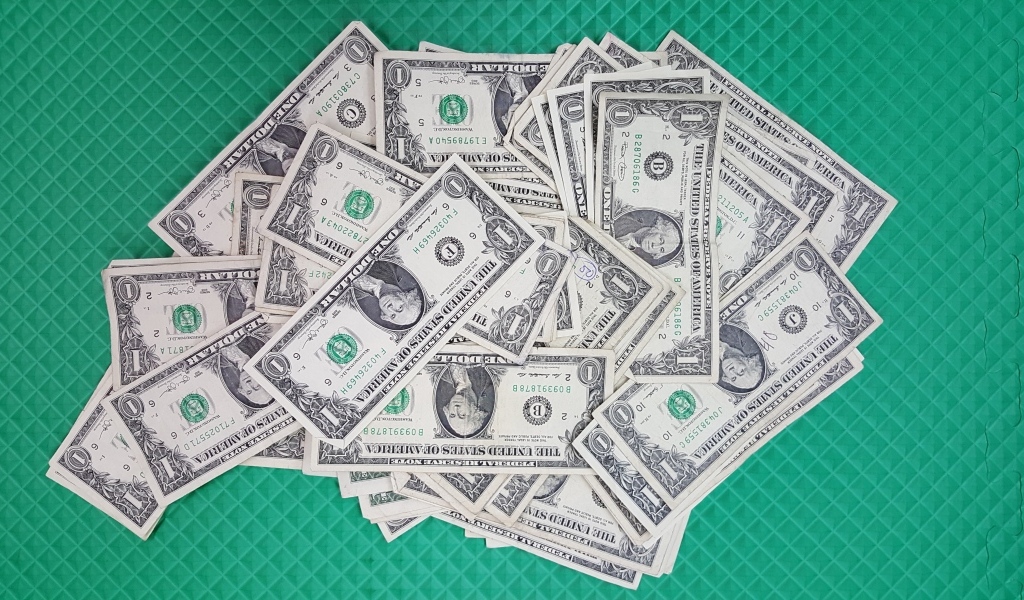 Много купюр в один доллар на зеленой поверхности