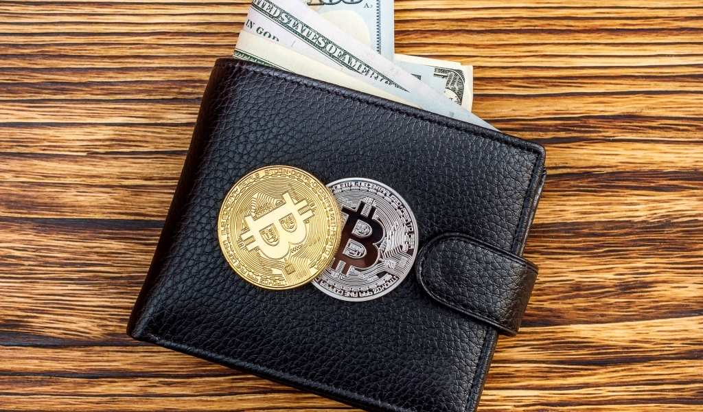 Черный кожаный кошелек с долларами и монетами биткоин