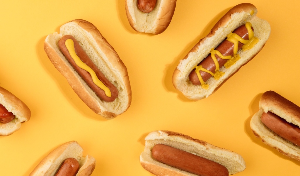 Аппетитные хот доги на желтом столе