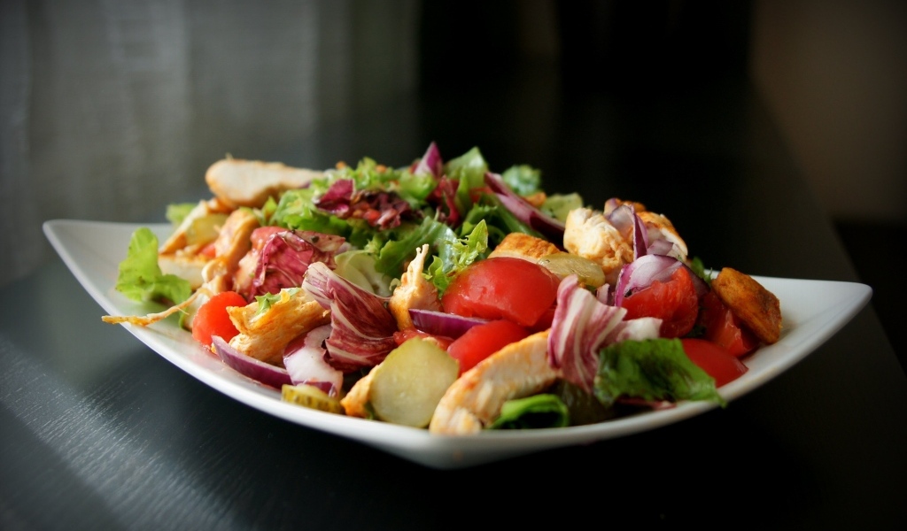 Аппетитный салат в белой тарелке на черном фоне