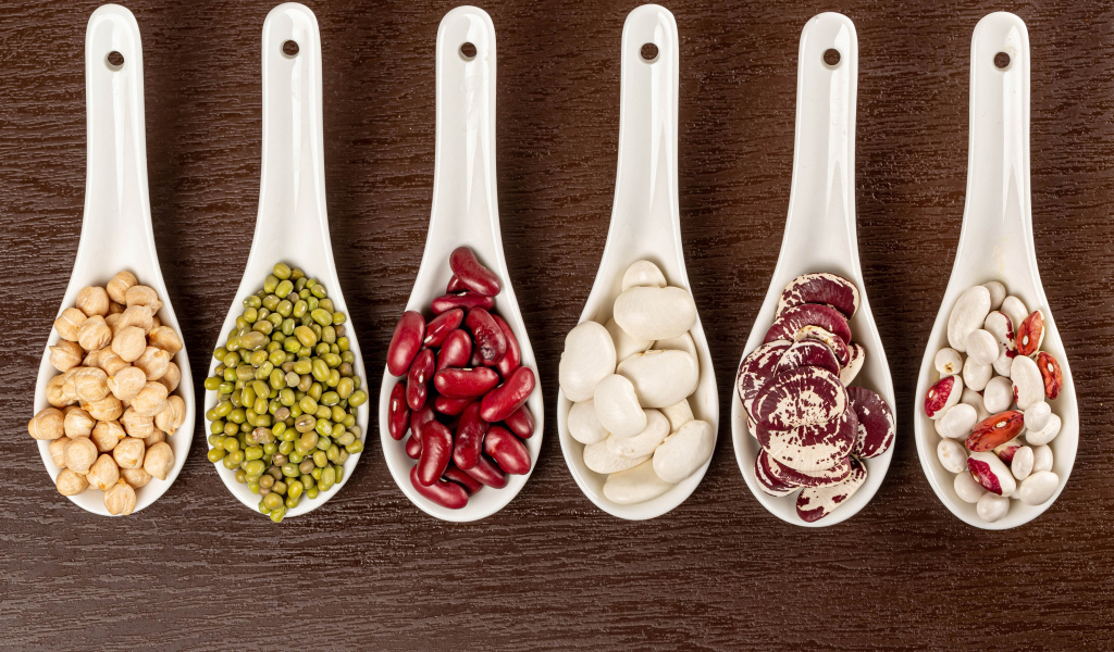 Бобовые зерна в белых ложках на столе
