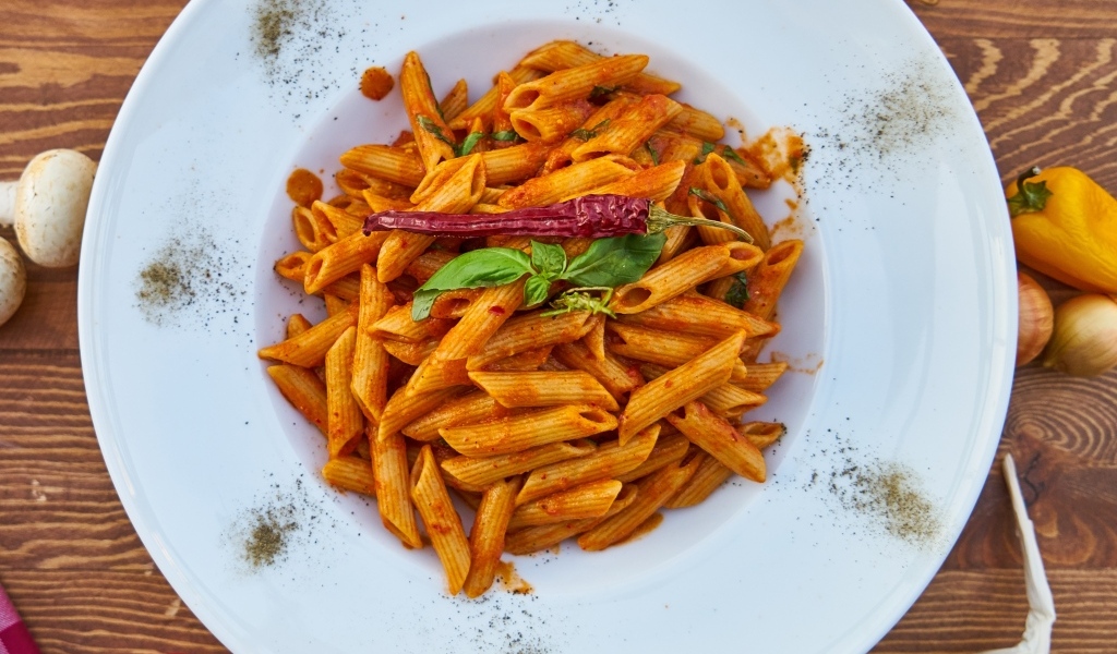 Вареные макароны на большой тарелке с красным перцем