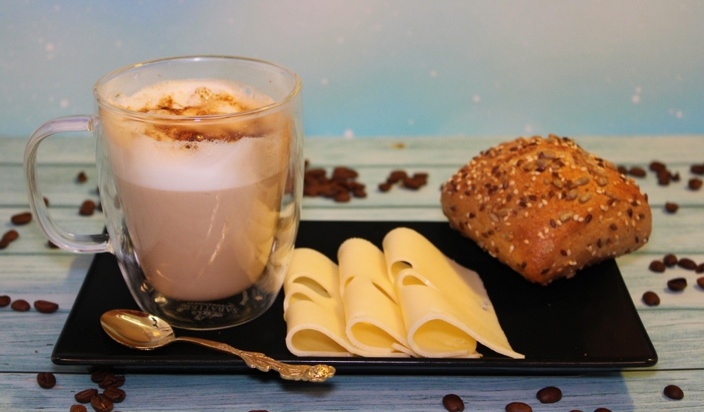 Сыр на тарелке с какао и булочкой