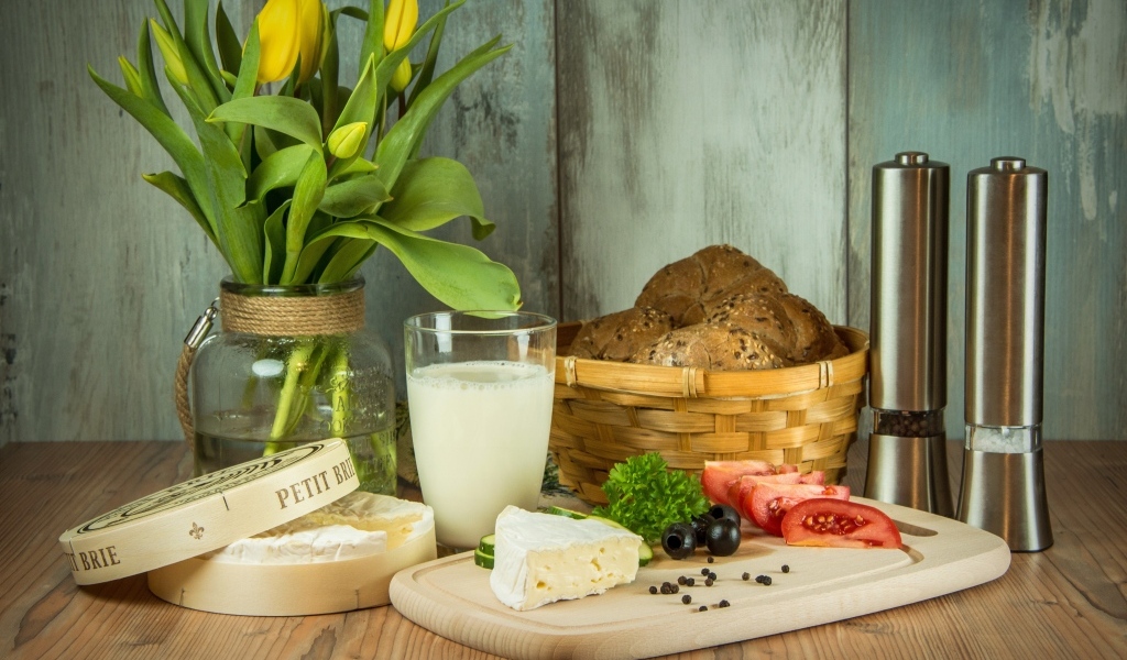 Сыр с овощами на столе с хлебом и букетом тюльпанов