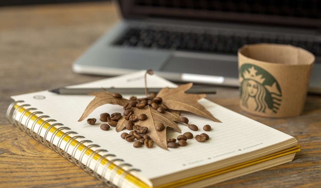 Зерна кофе с листом и блокнотом на столе