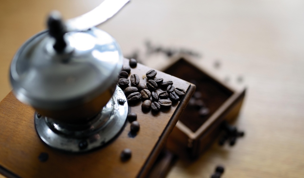 Кофемолка на столе с зернами