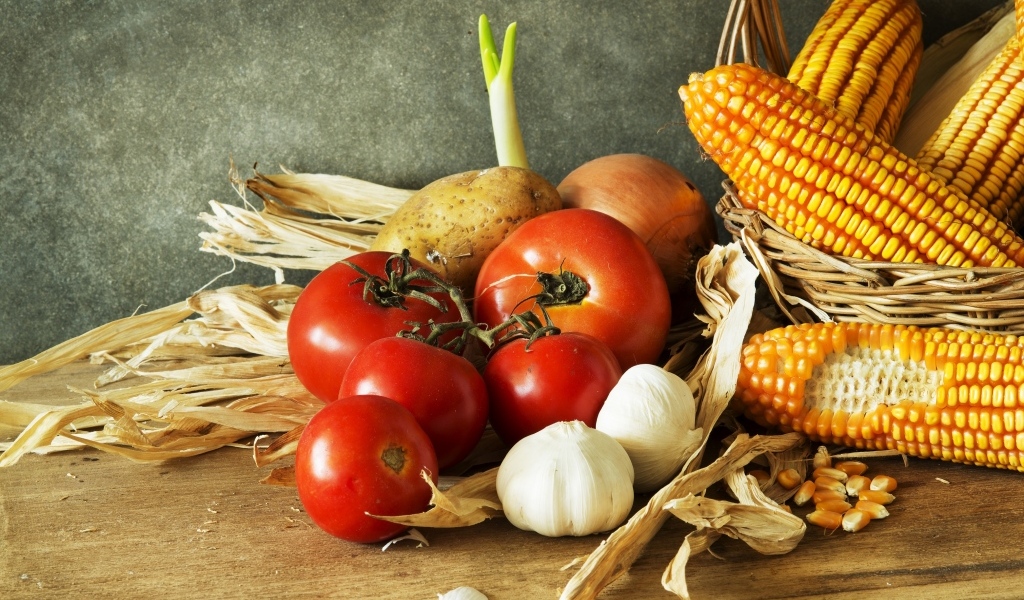 Кукуруза, чеснок и помидоры на столе