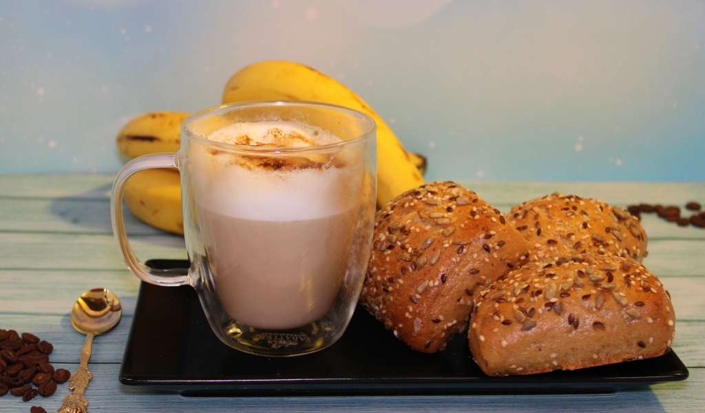 Чашка какао на столе с булочками и бананами