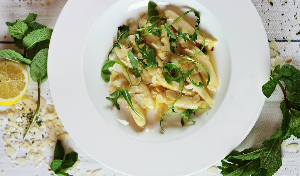 Блюдо с листьями рукколы в большой белой тарелке