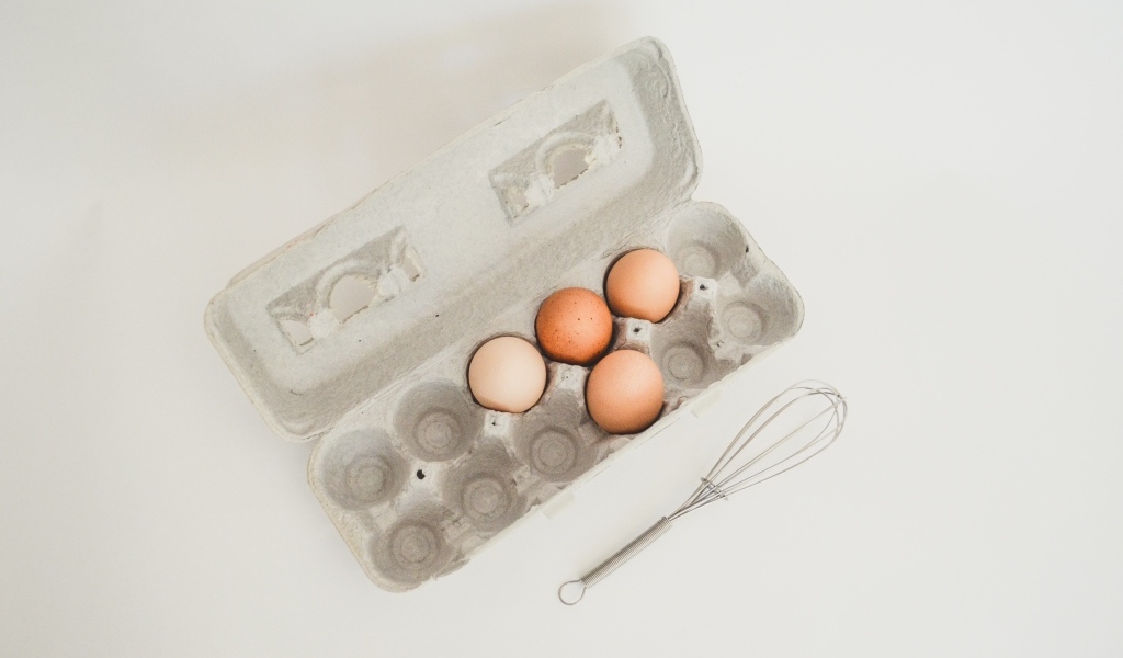 Четыре яйца в лотке на сером фоне