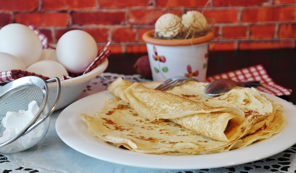 Свежие блины на столе с яйцами