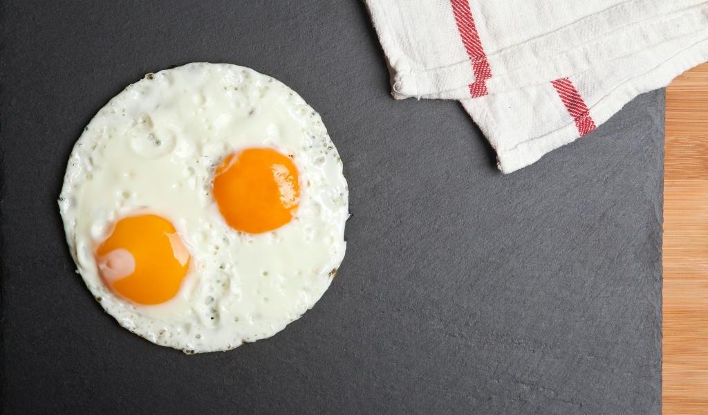 Яичница глазунья на сером столе с полотенцем