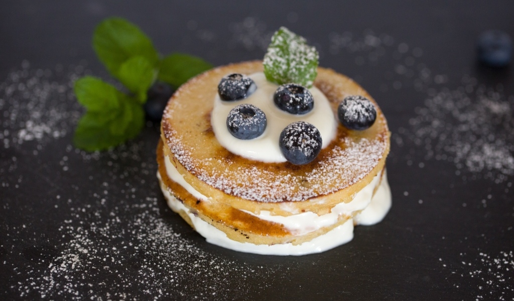 Оладьи с кремом и ягодами черники на столе