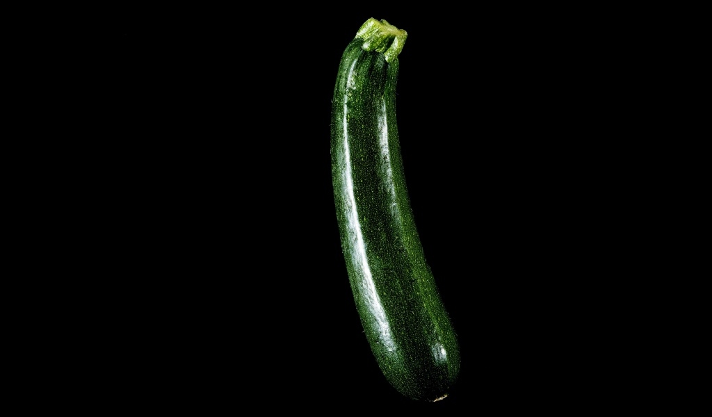 Зеленый кабачок на черном фоне