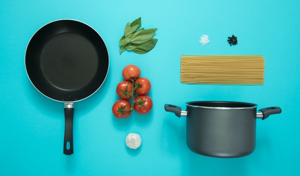 Ингредиенты и посуда для спагетти на голубом фоне