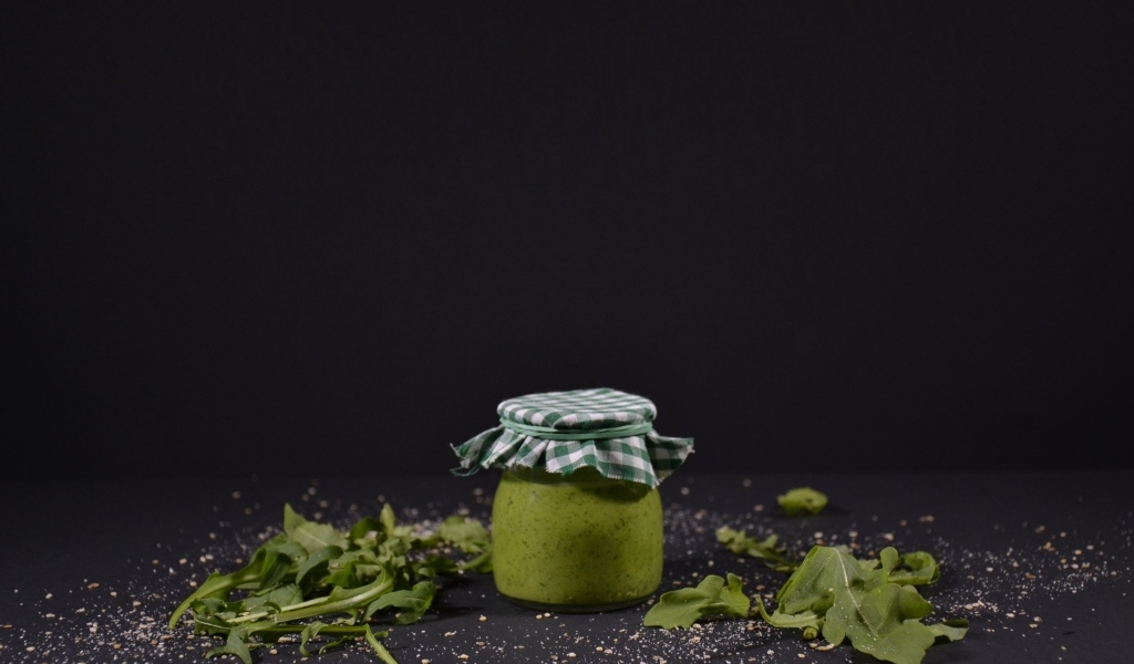 Банка соуса песто на черном фоне